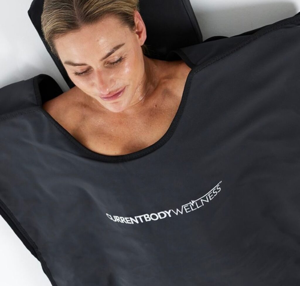 Femme allongée sous une couverture de sauna infrarouge, dans un cadre de soin bien-être à Paris